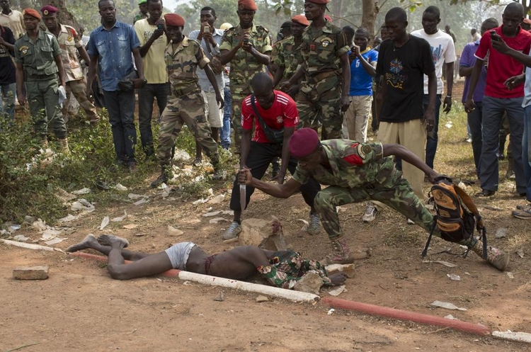 fot. Siegfried Modola / Reuters / 5 lutego 2014  Bangui, Republika Środkowoafrykańska  Żołnierz armii republikańskiej dźga nożem zwłoki człowieka poddanego egzekucji. Osoba ta podejrzewana była o dołączenie do wojowników Seleka.